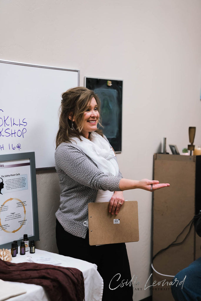 Tara, the labor skills workshop teacher at colorado baby, is standing in front of a white board and reaching her hand out to students (whom you can't see in the photo).